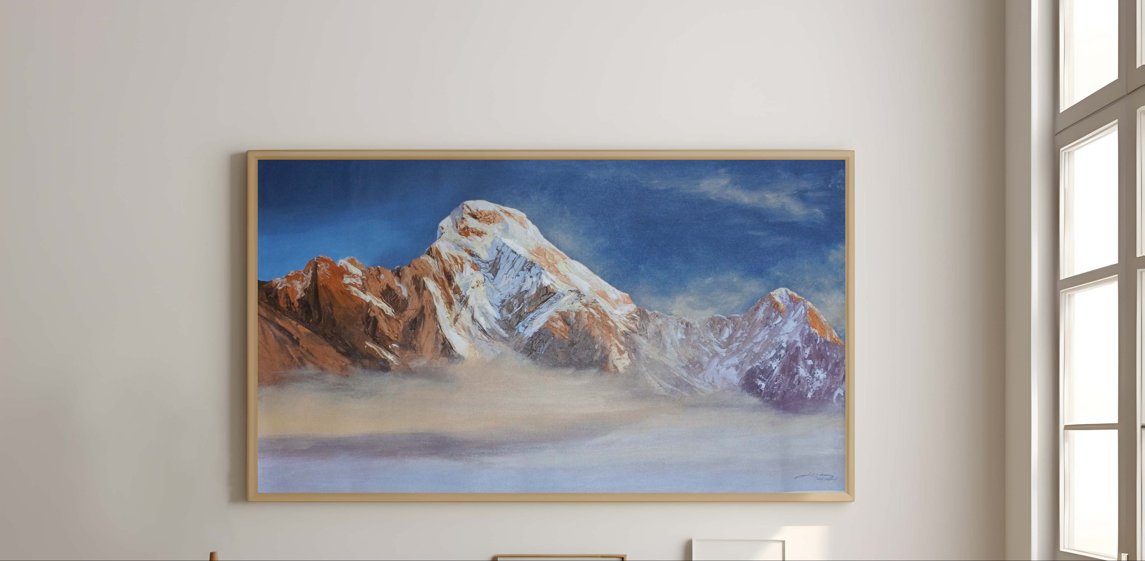 Framed mountain landscape painting above a wooden console table in a bright room.