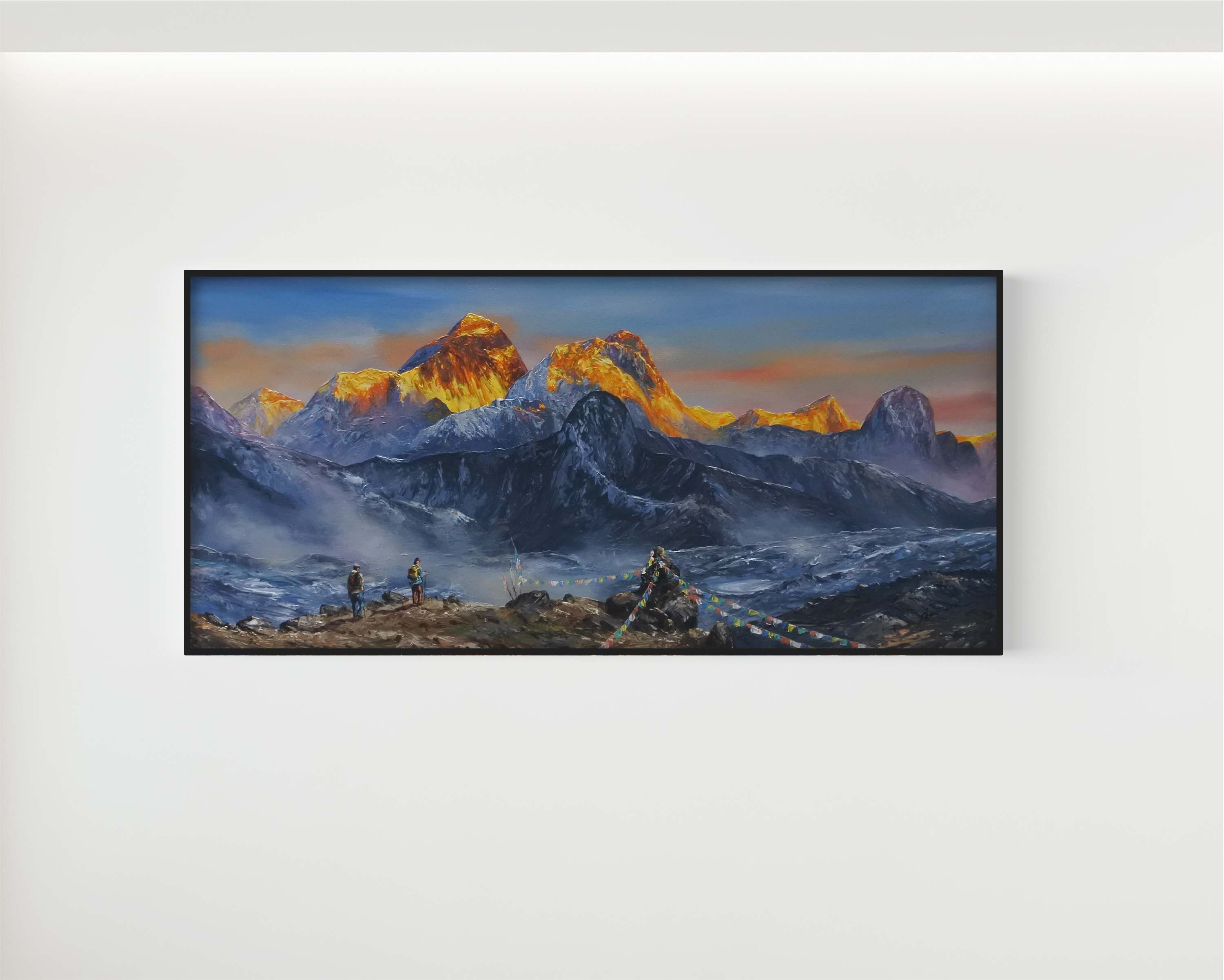 A framed horizontal landscape painting of snow-capped mountain peaks at sunrise, with golden-orange sunlit ridges and deep blue-gray shadows, displayed on a light gray wall.