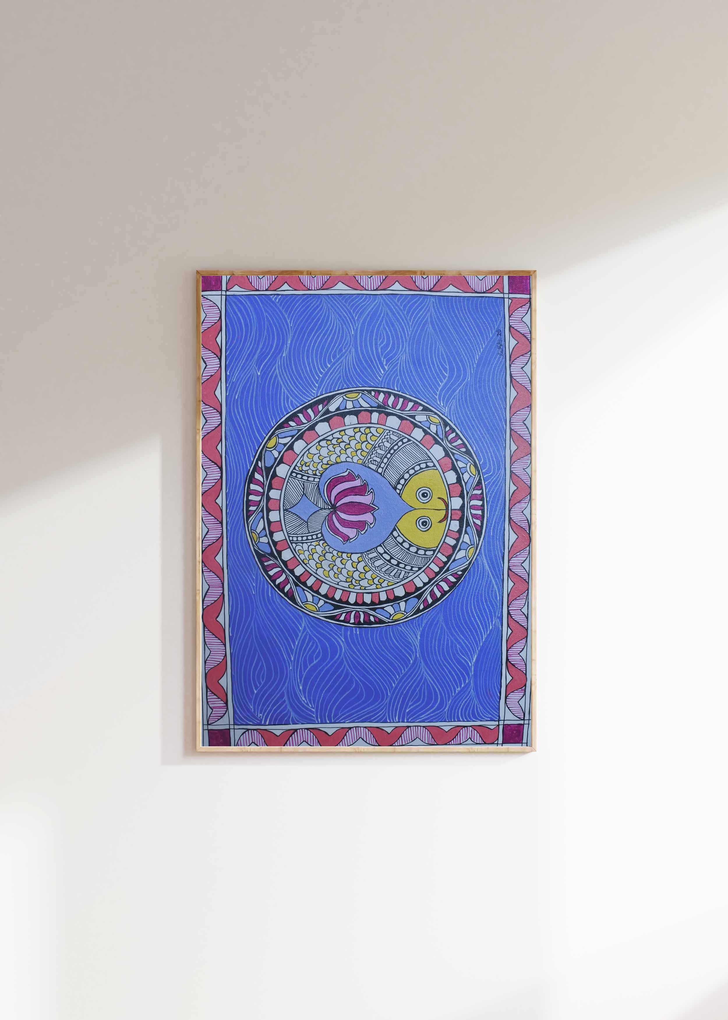 Framed artwork with a colorful circular design on a blue background, mounted on a white wall.